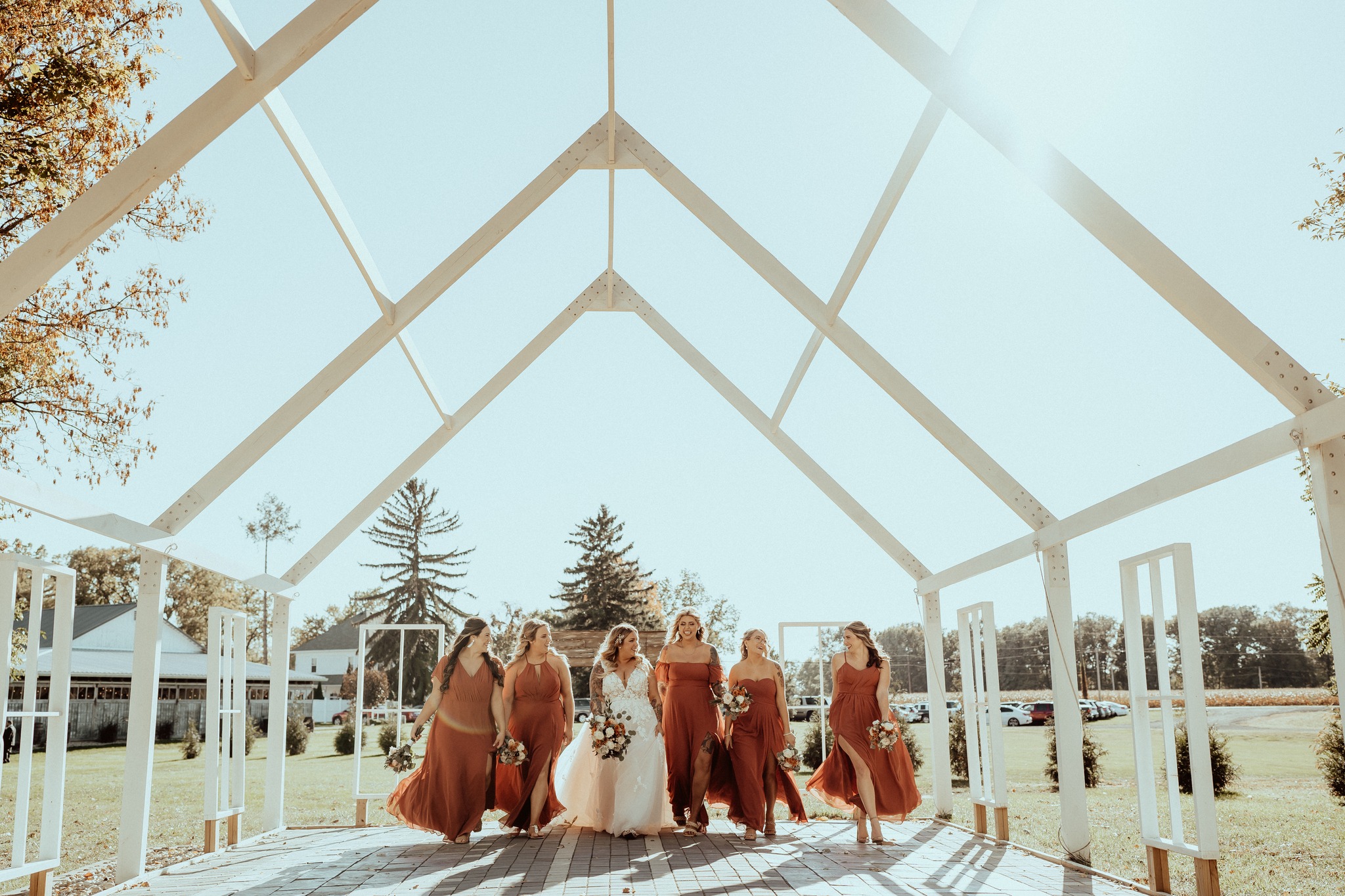 bride and bridesmaids walking under pergola