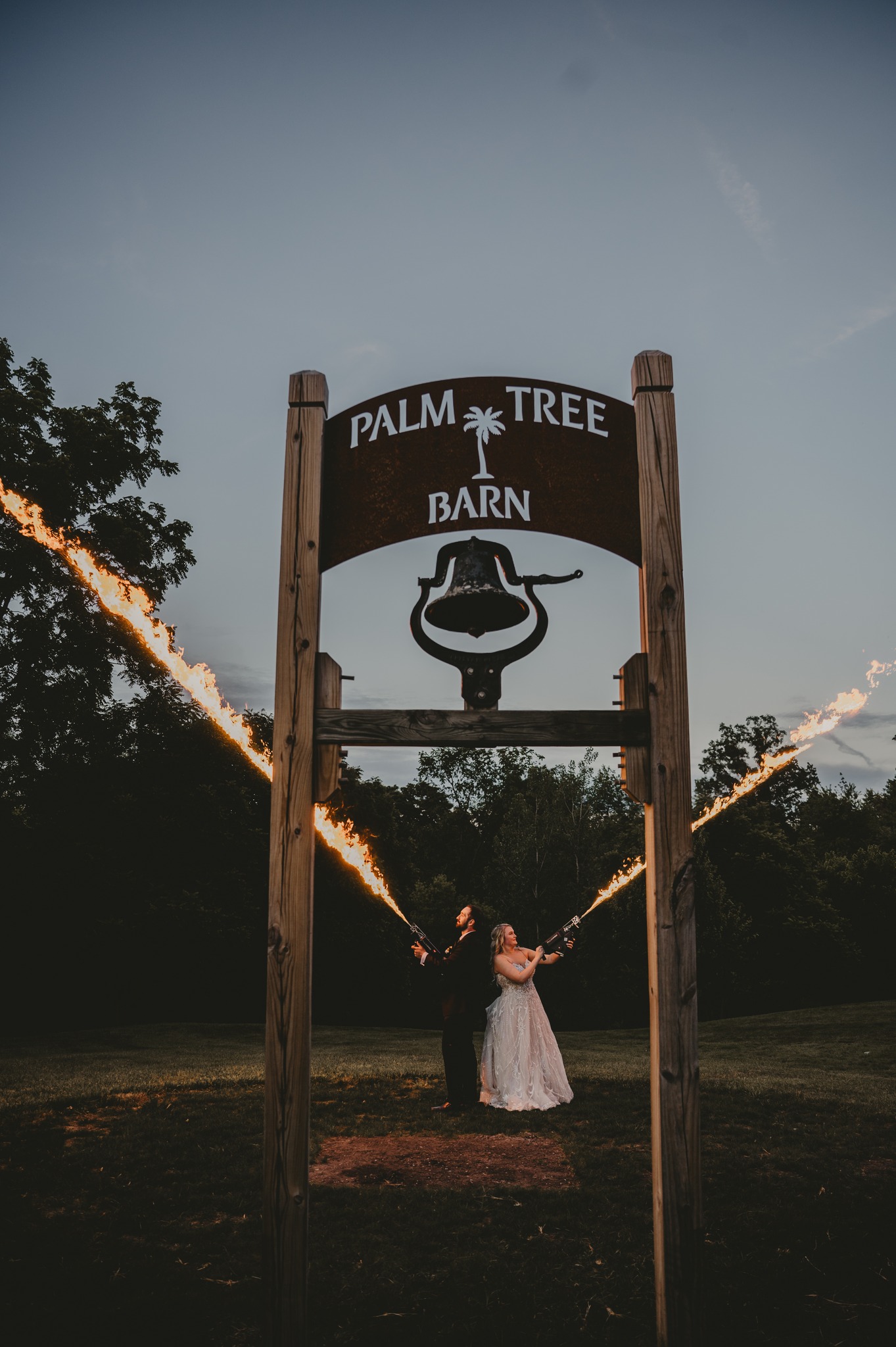 bride and groom behind palm tree barn sign