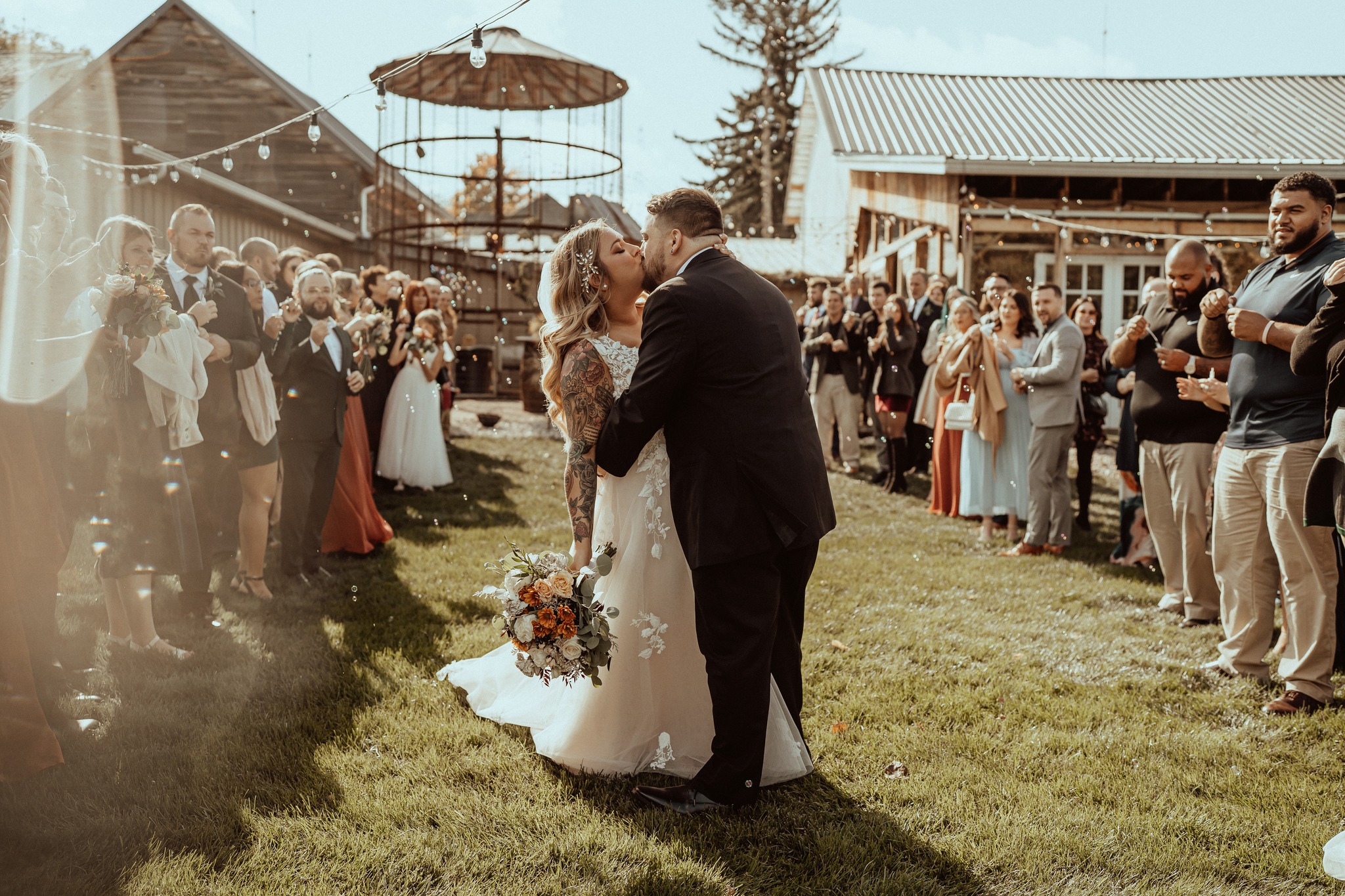 bride and groom kissing while guests blow bubbles