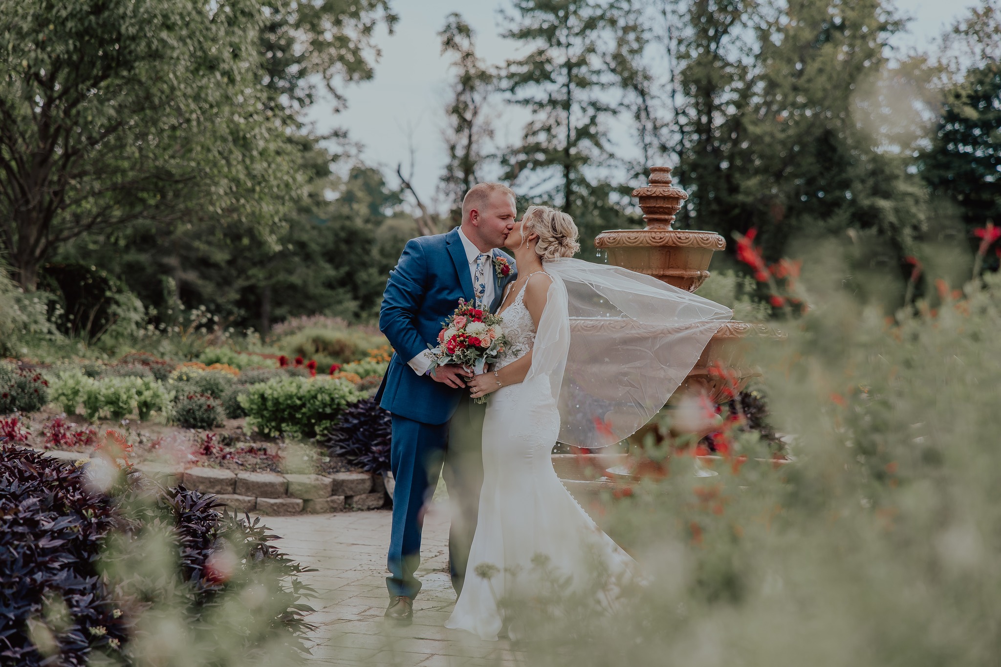 bride and groom kissing in front of fountain