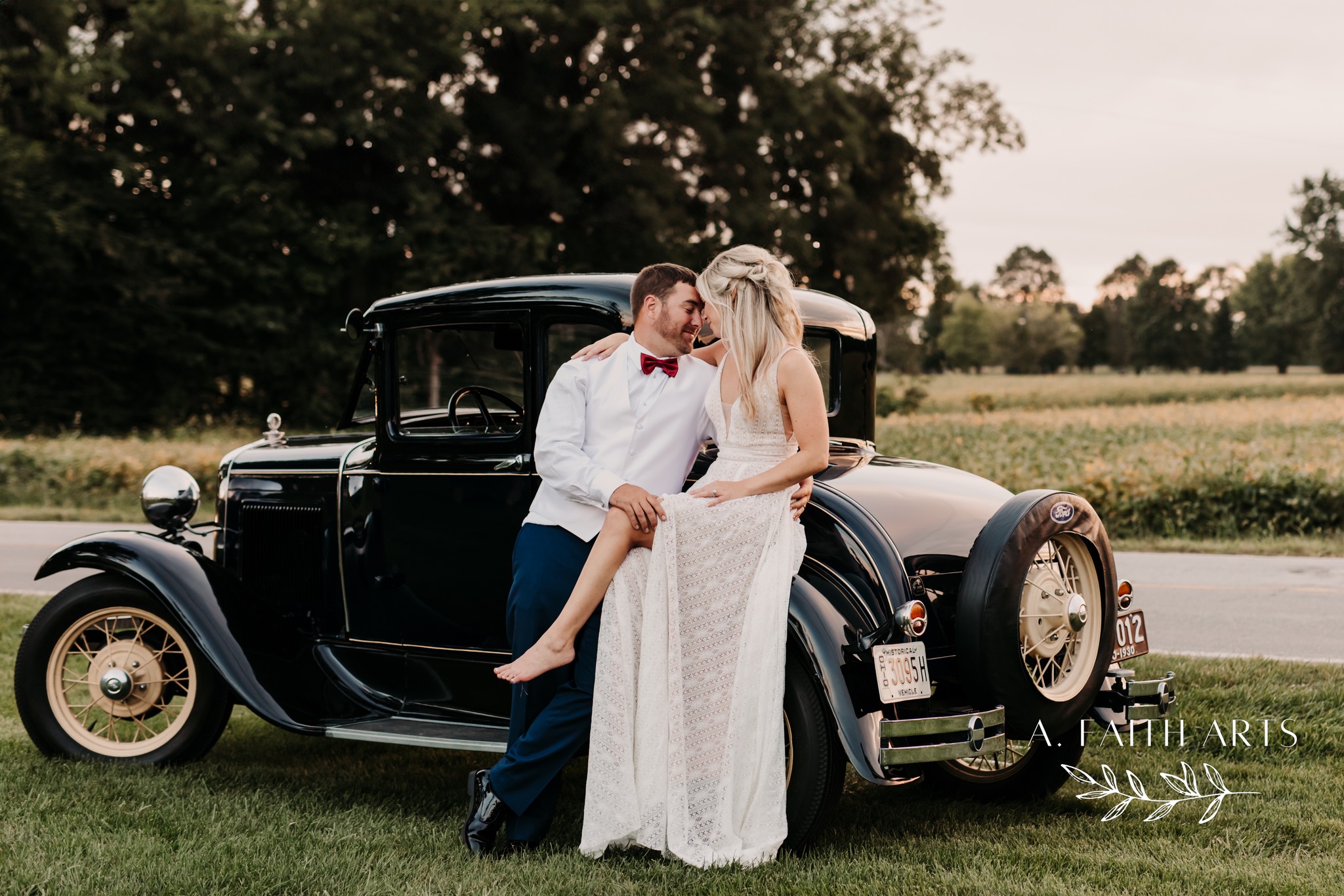 bride and groom posing with vintage car