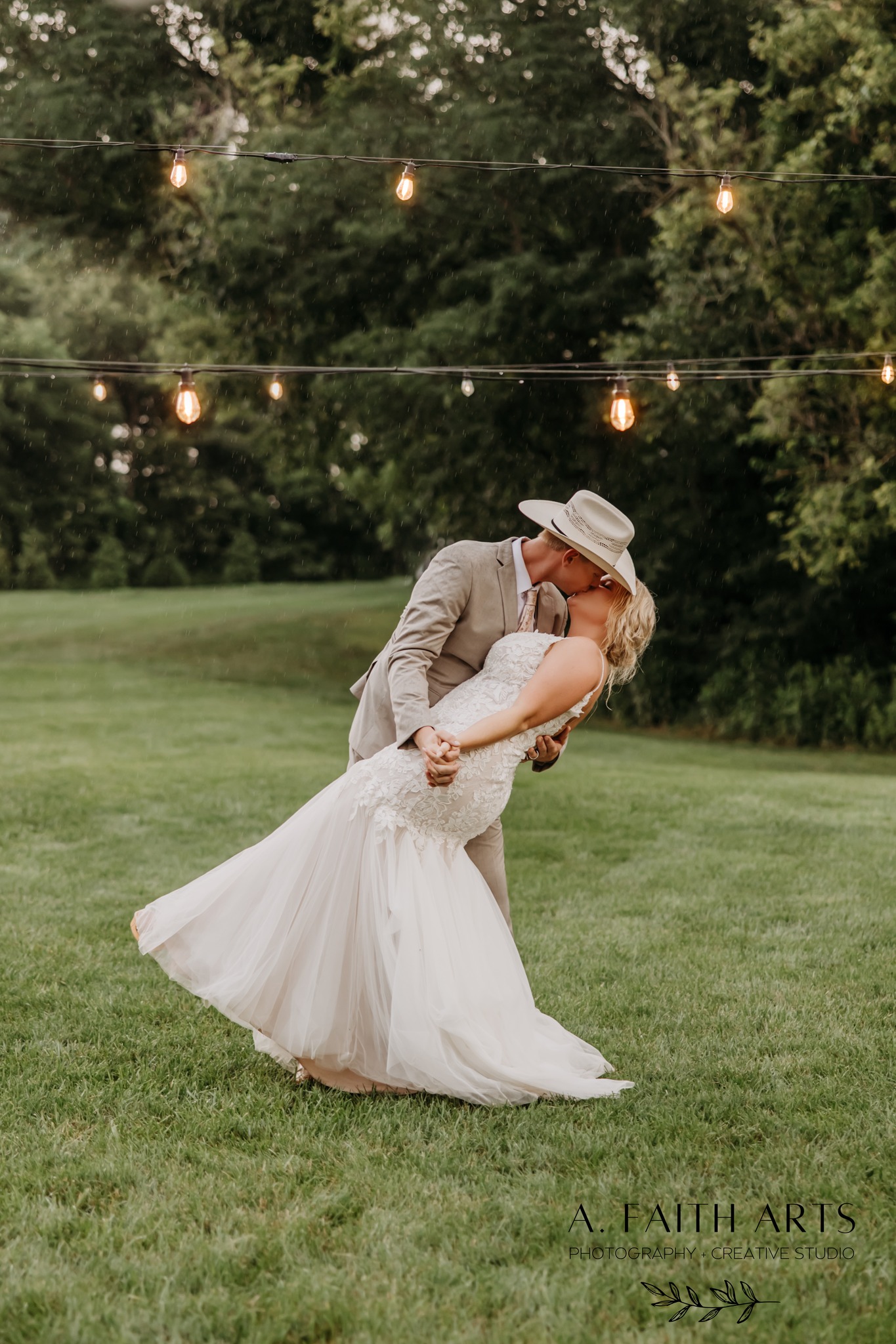 bride and groom kissing under string lights outdoors