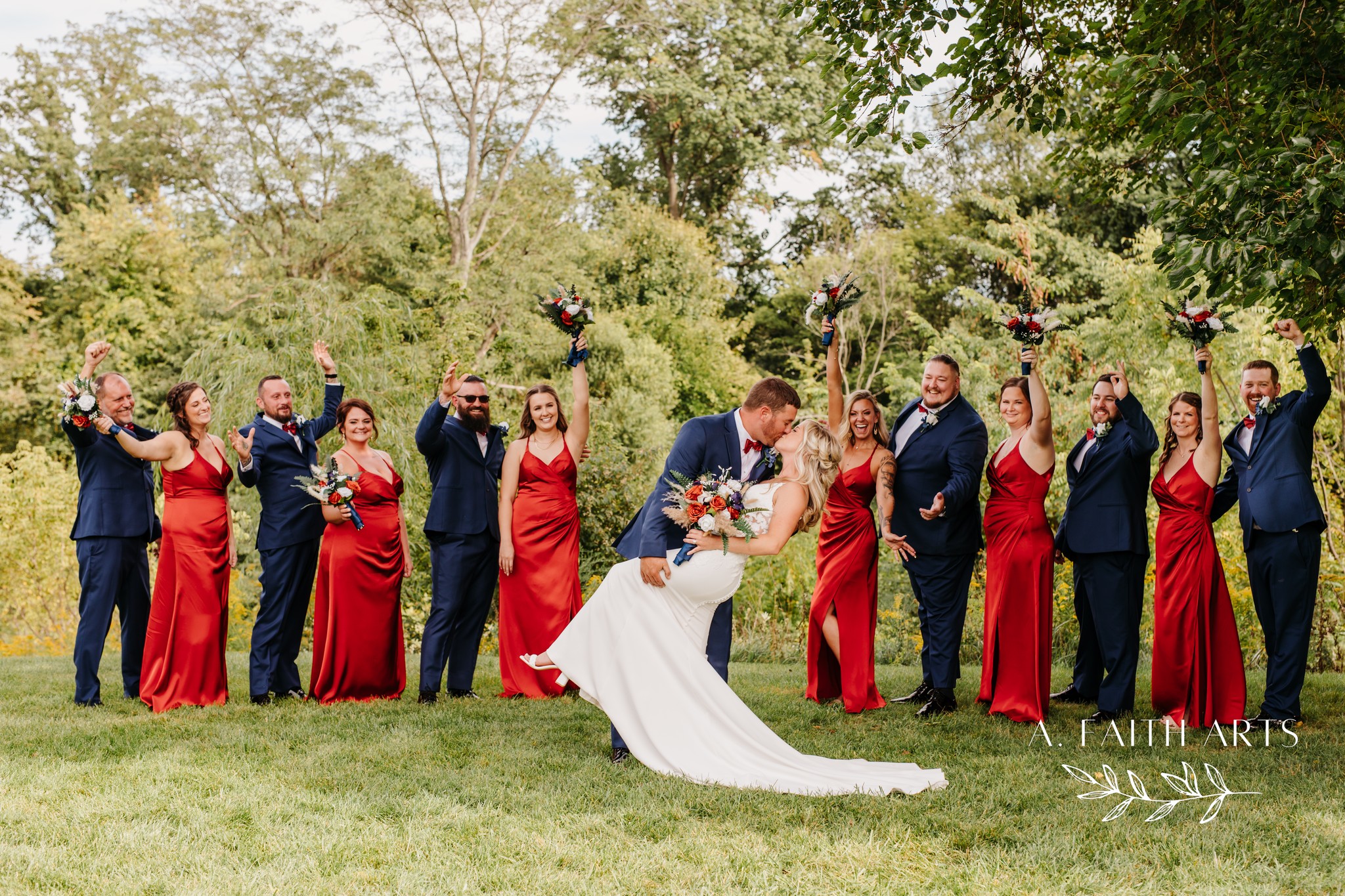 bride and groom kissing while wedding party cheers