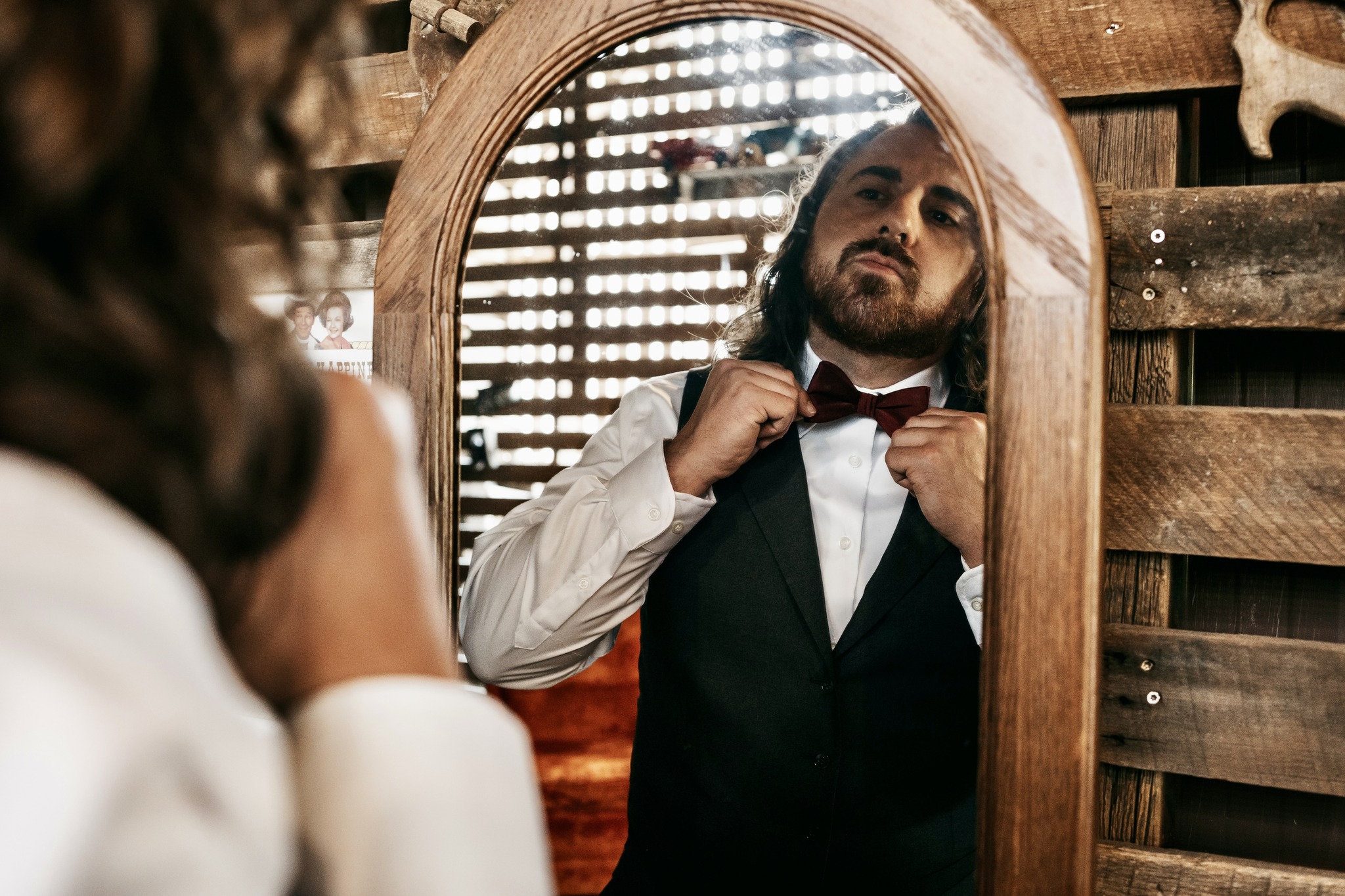 groom tying bow tie in mirror