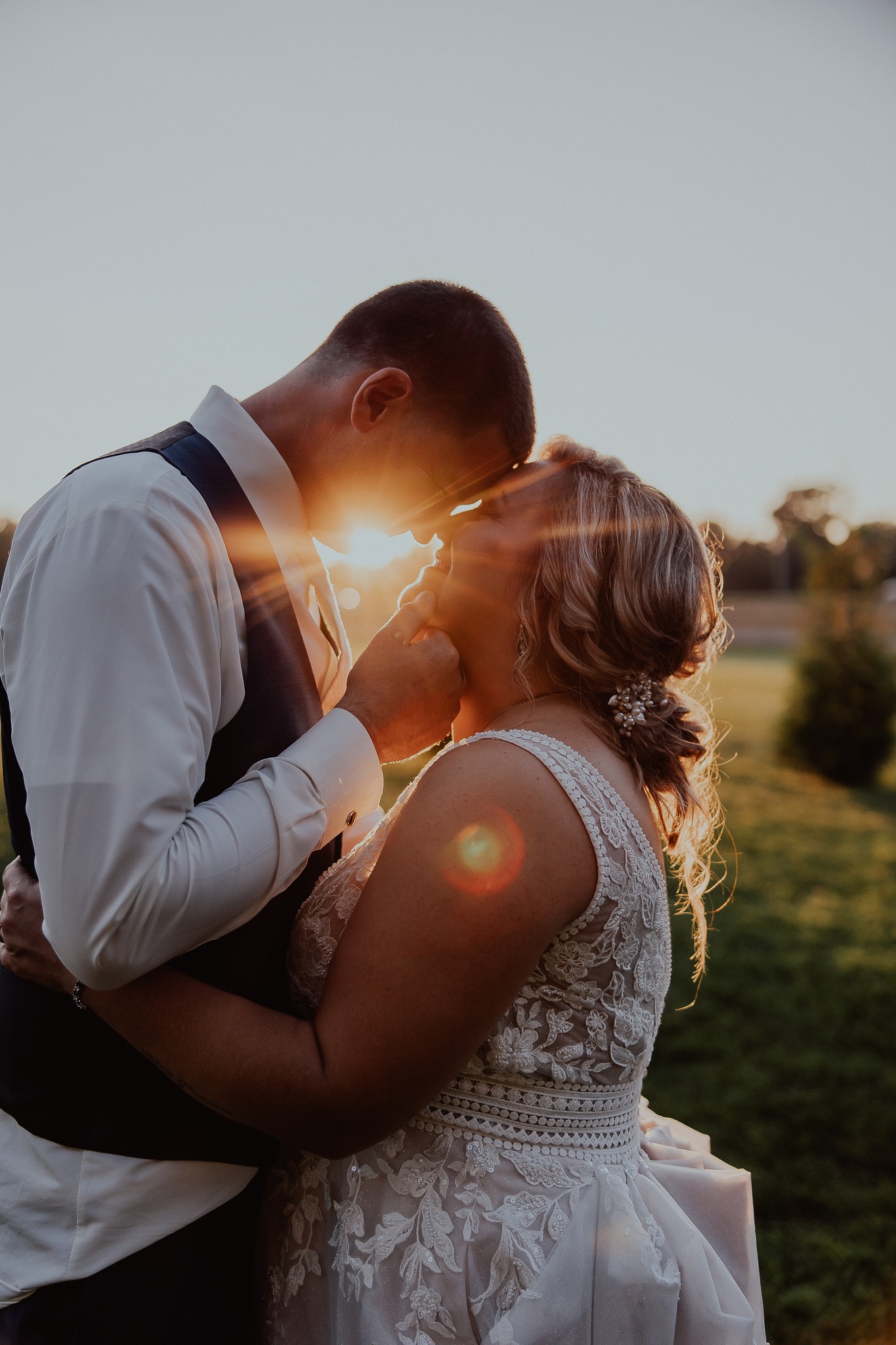 bride and groom kissing at sunset