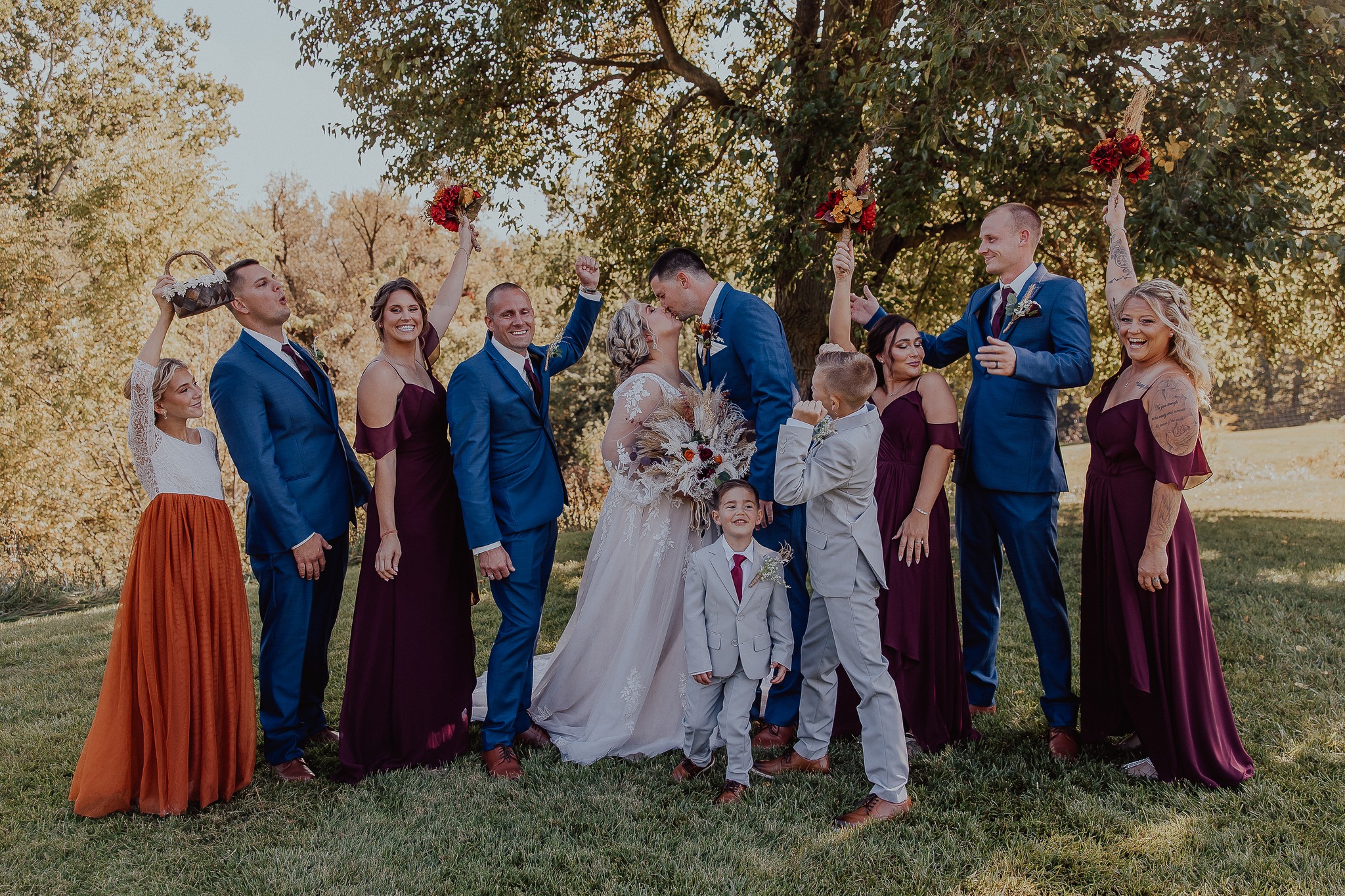 bride and groom kissing while wedding party cheers