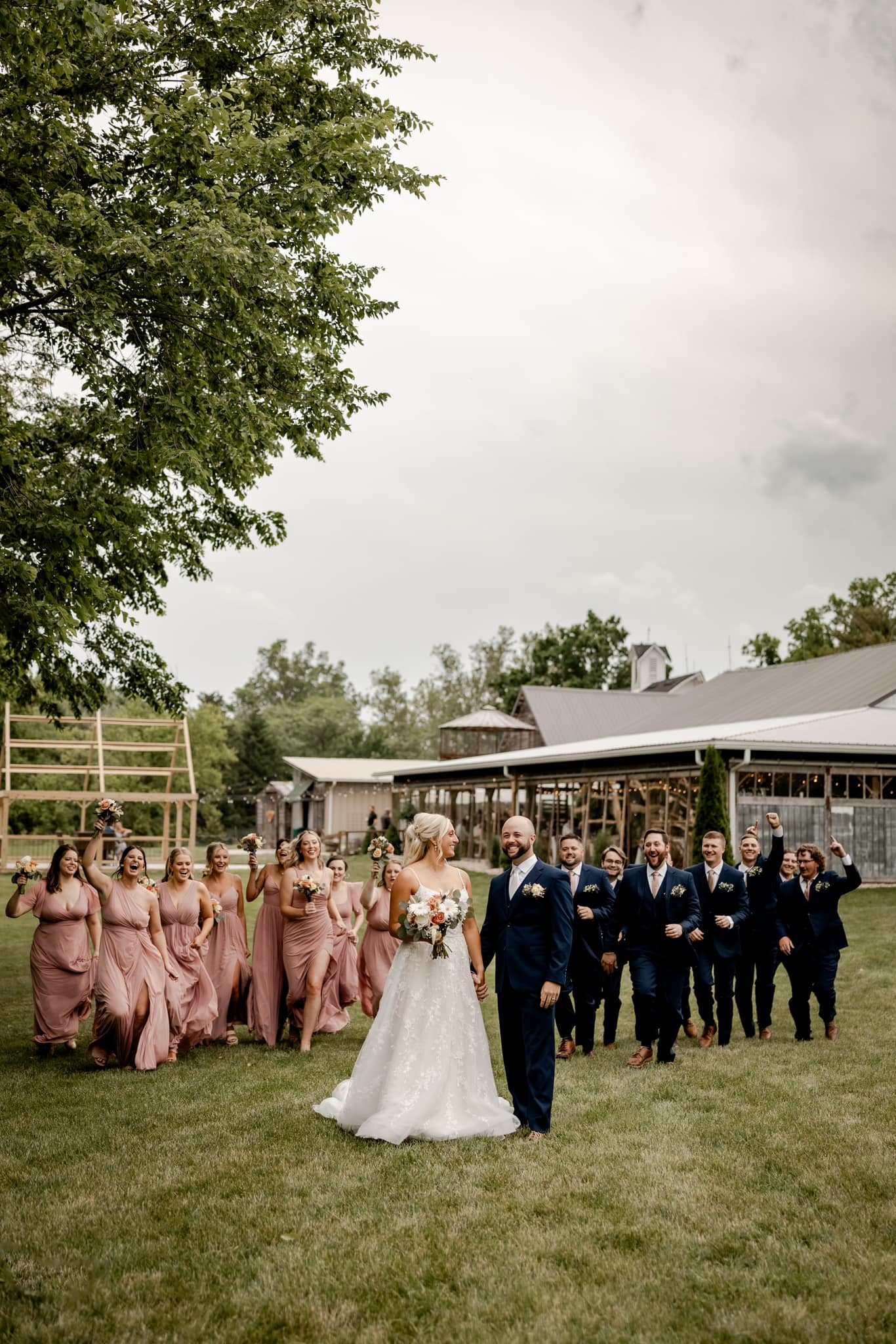 bride and groom holding hands with wedding party cheering behind them