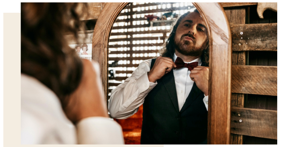 groom tying bow tie in mirror
